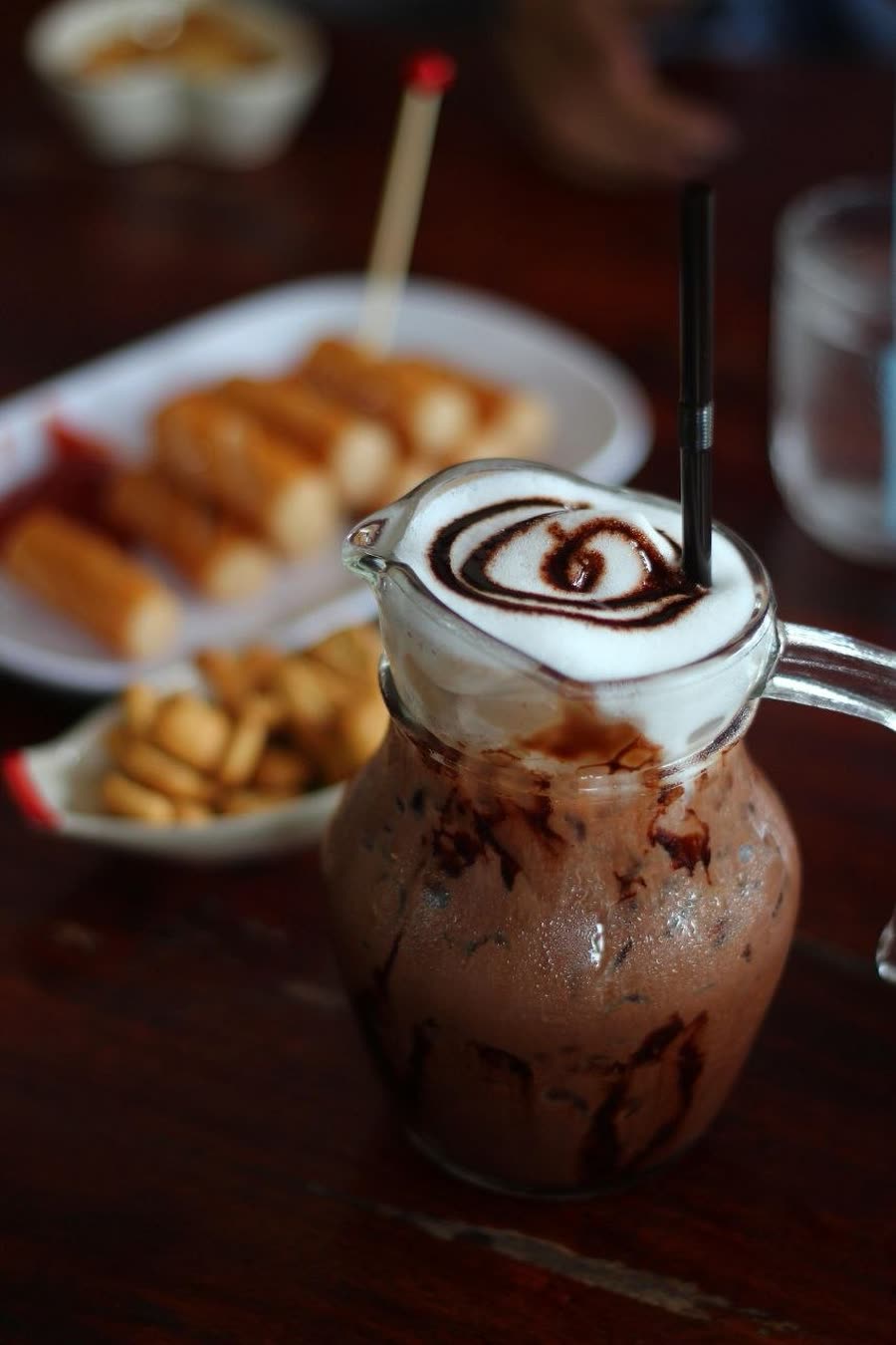 Bebida fría de chocolate con espuma servida en jarra de vidrio